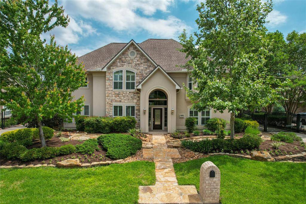 A grand first impression. This stunning two-story home boasts a stately stone facade, a graceful arched entrance, and meticulously maintained landscaping. Surrounded by mature trees, a charming stone pathway leads you to the welcoming front door, setting the tone for the beauty within.