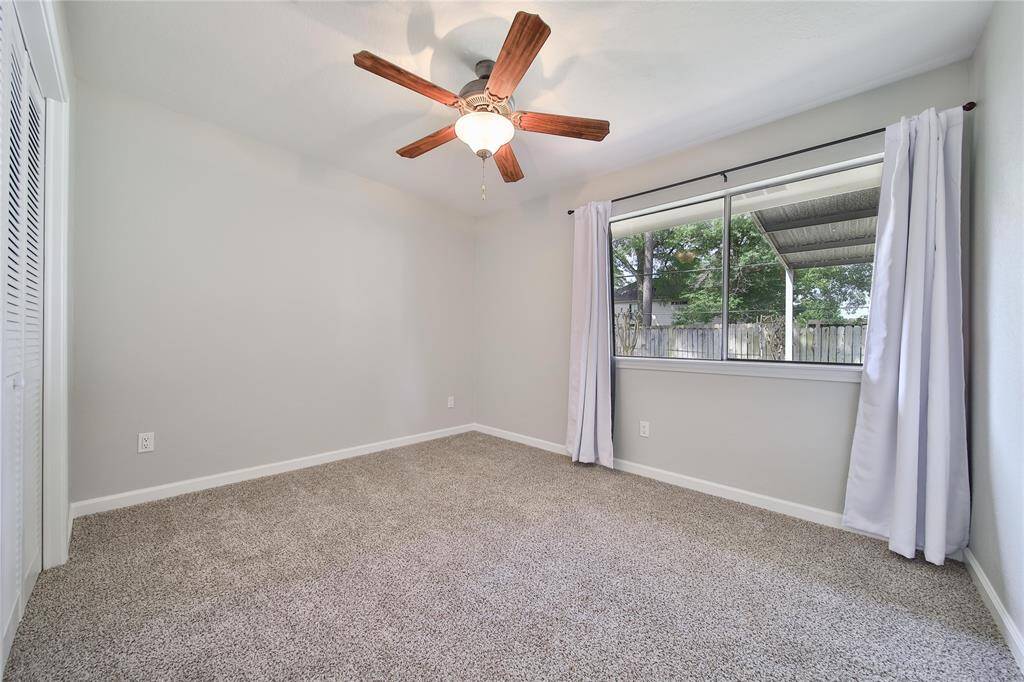 Secondary bedroom facing backyard, new closet doors, carpet and ceiling fan