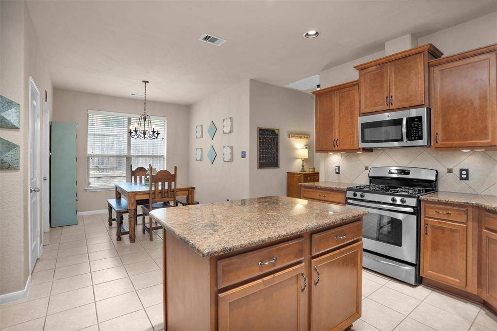 Experience the perfect blend of style and functionality in this kitchen, featuring a spacious granite island, modern stainless steel appliances, and warm wooden cabinetry. Perfect for cooking and entertaining.
