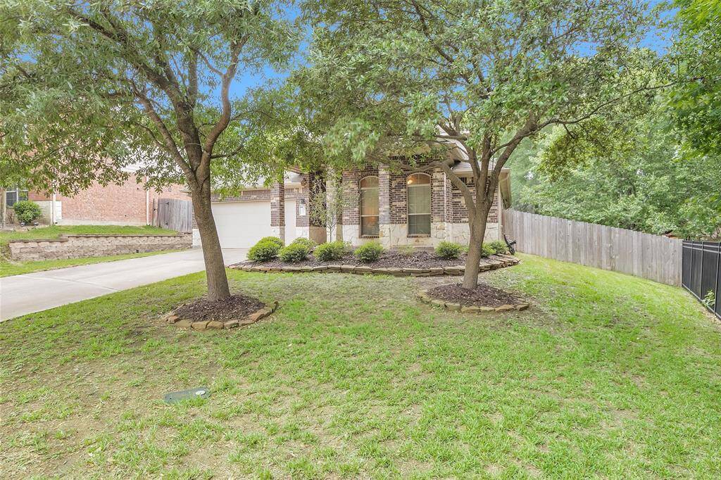 Charming brick home with a welcoming front yard featuring mature trees and well-maintained landscaping. The property includes a driveway leading to a spacious garage, offering convenience and curb appeal.