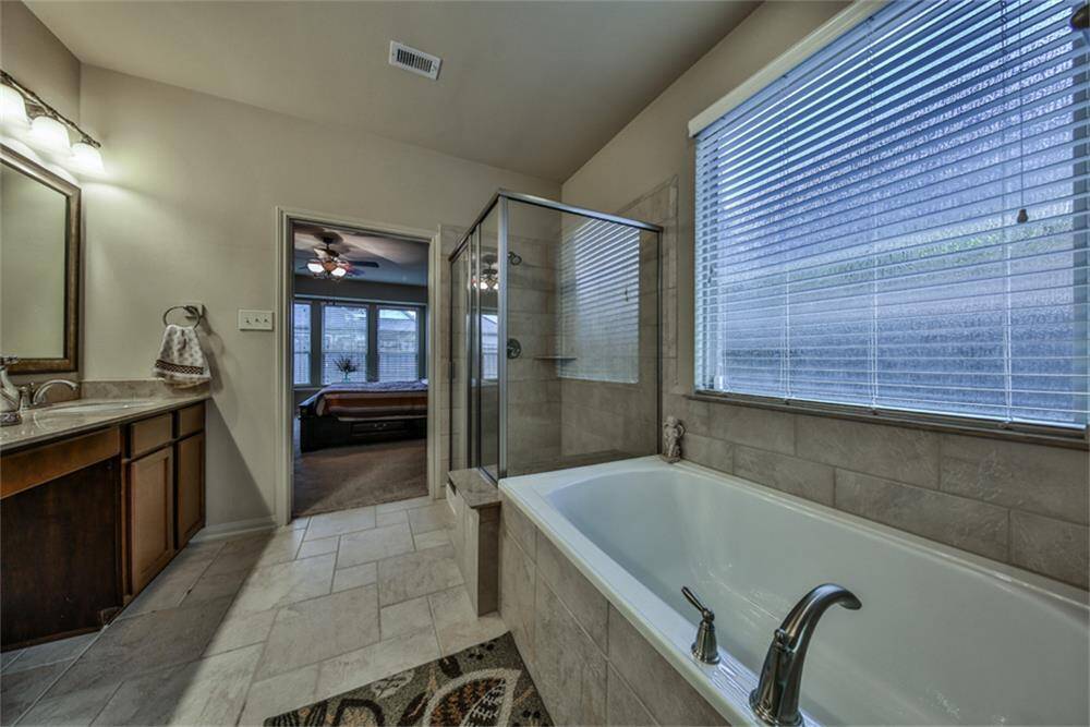 The spa-like master bath features a deep soaking tub beneath an upgraded frosted glass window that fills the space with soft natural light. Enjoy a large walk-in shower with upgraded tile surround and built-in bench for added comfort.