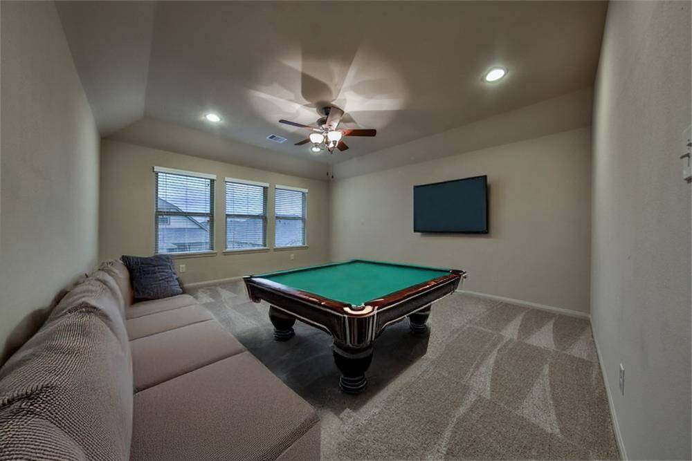 Spacious game room with soaring ceilings, an upgraded ceiling fan, and plenty of room for fun and relaxation.