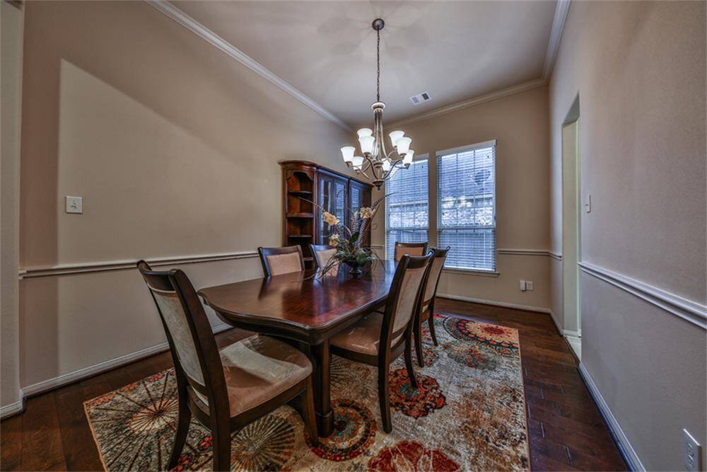 Spacious formal dining room features elegant crown molding, classic chair railing, rich wood floors, and direct access to the gourmet kitchen—perfect for effortless entertaining!