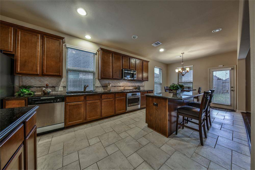 Gourmet kitchen loaded with upgrades! Features a large eat-in island with striking granite countertops and waterfall edges for a custom, high-end look. Upgraded large-format tile flooring laid in a designer pattern, plus a water softener, water purifier, and more!