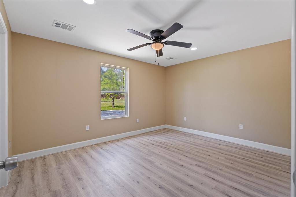 This room features neutral walls, light wood flooring, and a ceiling fan. A single window provides natural light, offering a cozy and inviting space.