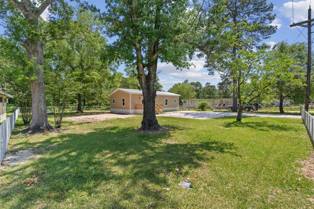 This property features a cozy single-story home surrounded by lush greenery and mature trees. The spacious yard offers ample room for outdoor activities, and a driveway provides convenient parking. It's a serene setting ideal for those seeking a peaceful environment.