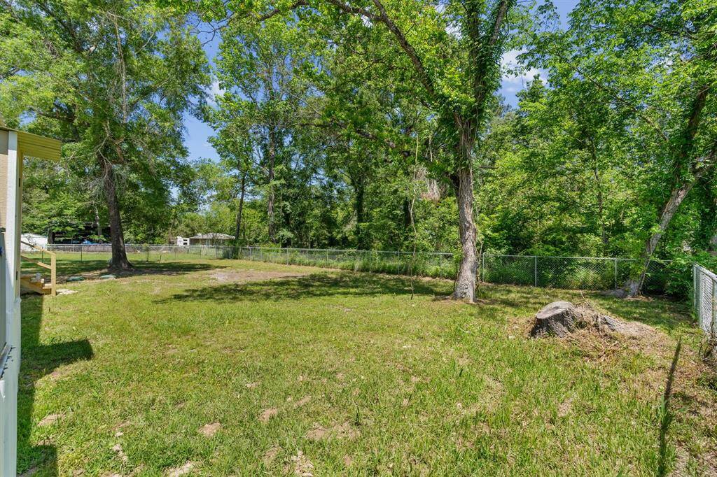 Spacious backyard with lush greenery, mature trees, and a fence, offering a serene and private outdoor space.