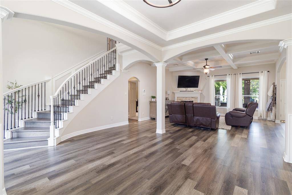 This spacious living area features a modern open-concept design with a cozy seating area with a fireplace and a great view of the backyard. Ample natural light streams in from large windows, creating a warm and inviting atmosphere.