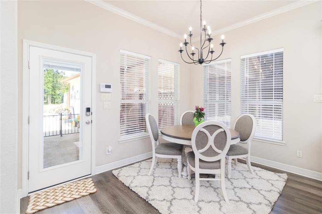 Bright breakfast area with large windows, neutral walls, and a modern chandelier.