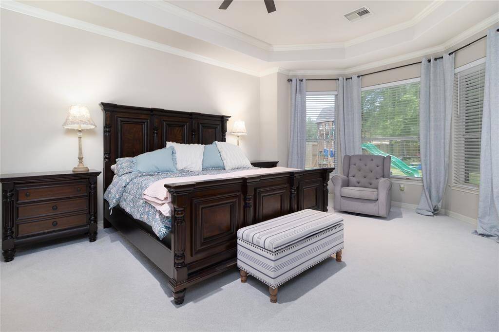 This spacious primary bedroom features large windows offering plenty of natural light and a view of the outdoors.