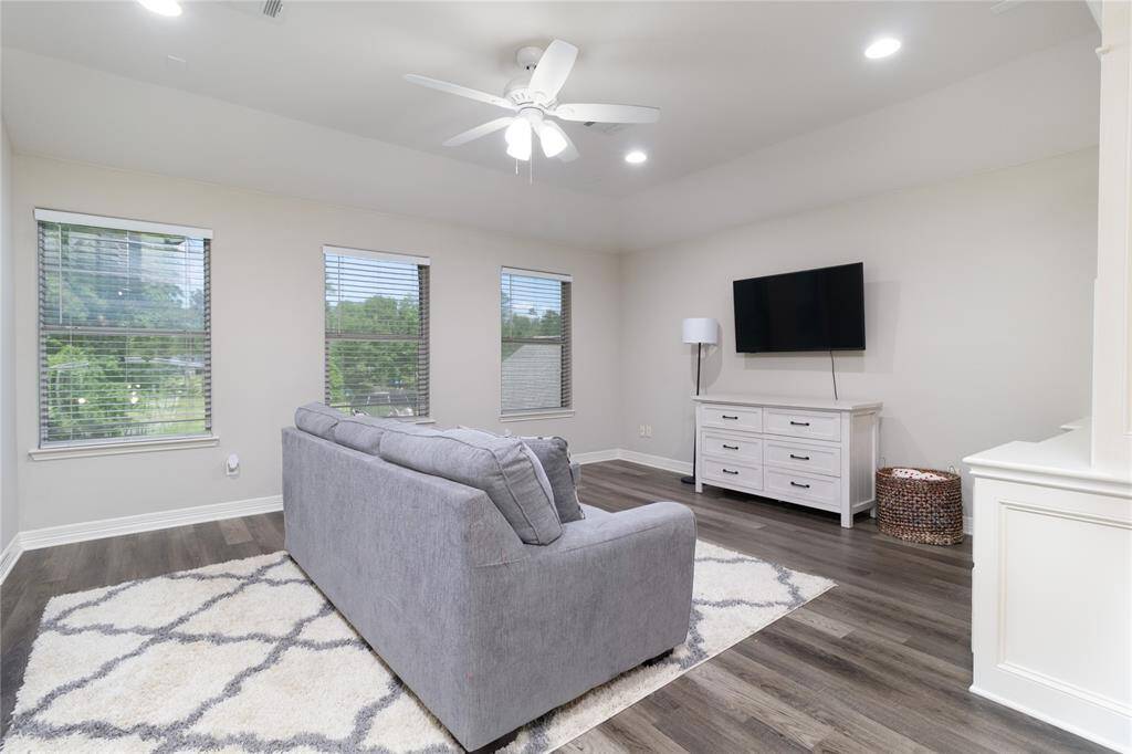 This spacious game room features a modern design with built ins. Three large windows provide ample natural light, while the ceiling fan and recessed lighting enhance comfort.