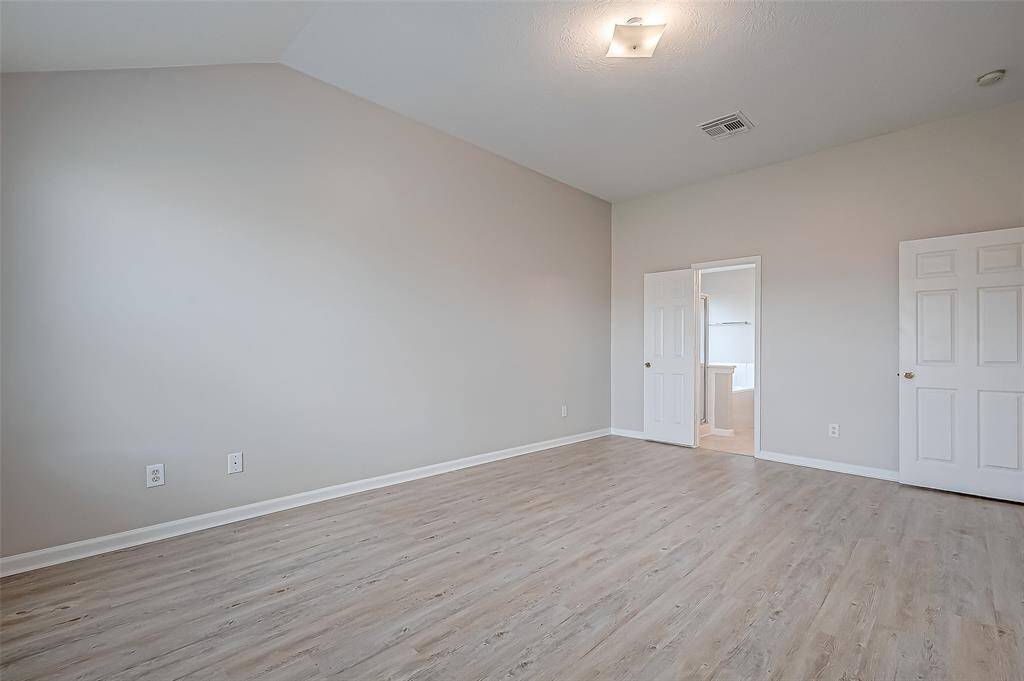 The primary bedroom is defined by a generous amount of space, with gently sloping ceilings adding architectural interest.