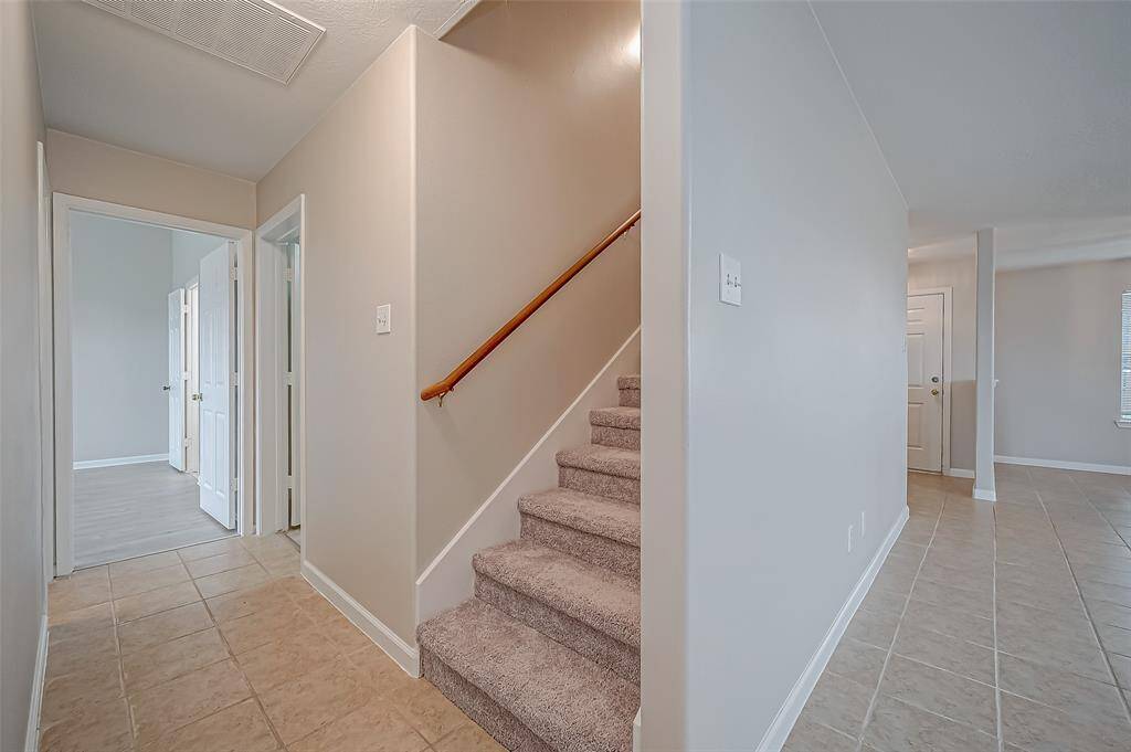 The staircase, centrally positioned between the living room and primary bedroom, is carpeted for added comfort.