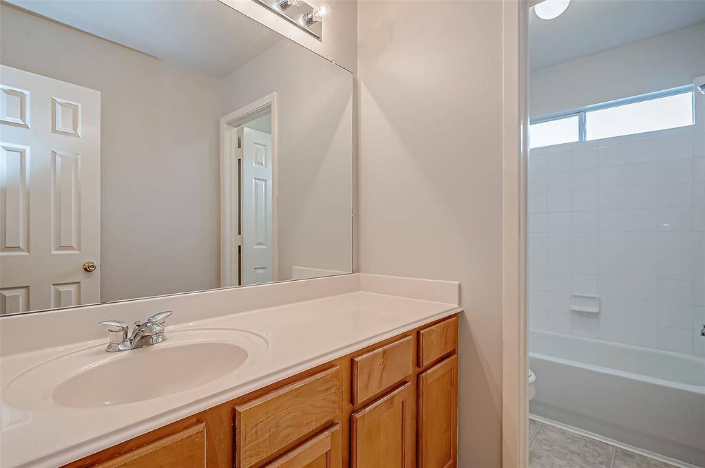 Inside the bathroom, a well-lit vanity space is set apart from the shower and tub, ensuring a functional layout.