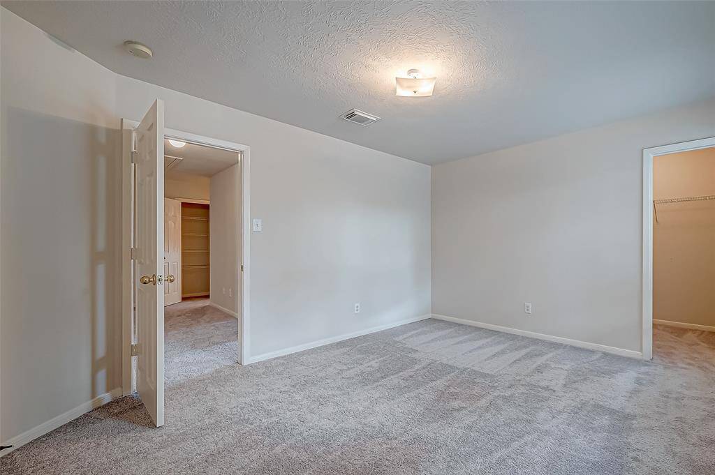 Another bedroom features a neutral palette and plush carpeting, with a built-in closet offering practical storage.