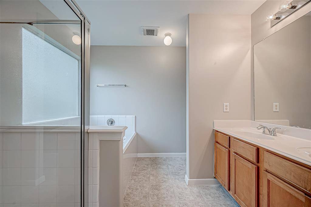 The primary bathroom is designed for comfort, featuring a spacious vanity area with dual sinks, a large mirror, and stylish lighting.