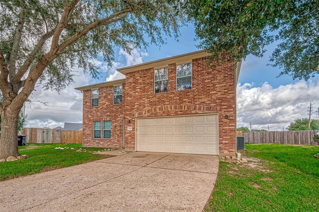 The wide driveway provides ample parking, leading to the recessed front entryway. The home’s facade presents a balanced combination of structure and open space.
