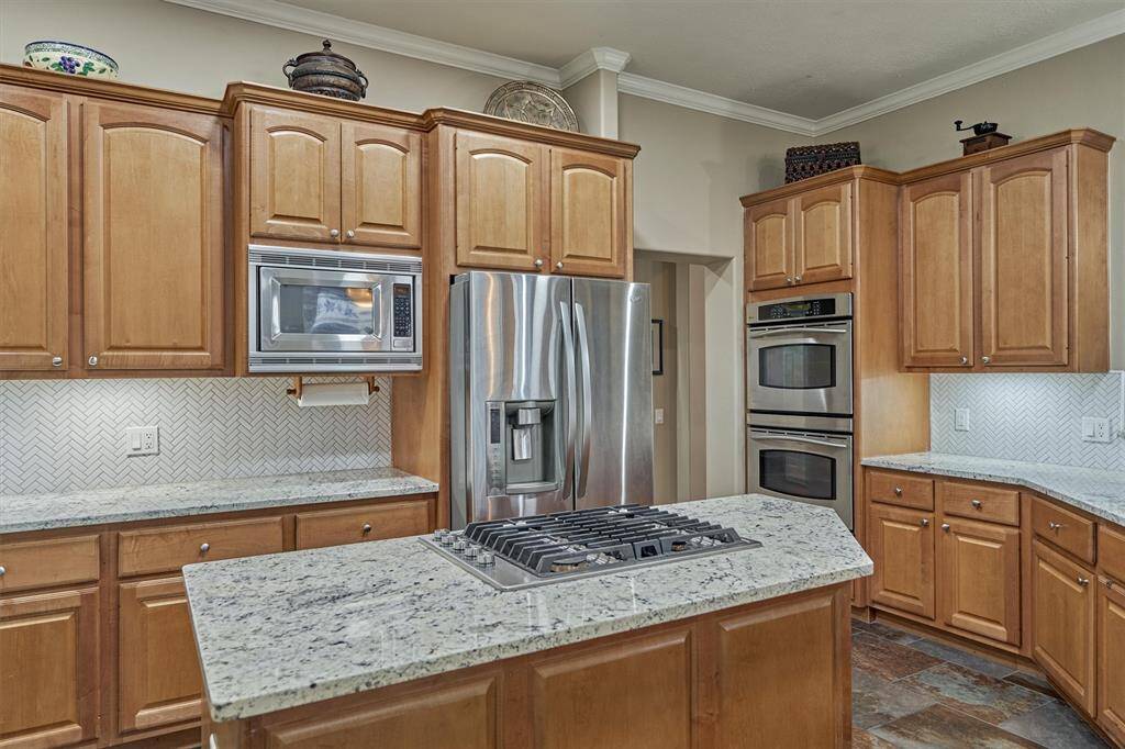 The kitchen is equipped with stainless-steel appliances, featuring double ovens, a built-in microwave, a gas cooktop and undercounter lighting.