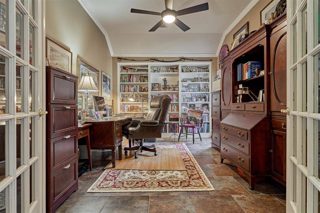 The office is situated at the front of the house, featuring built-in shelves, French doors, and high ceilings.