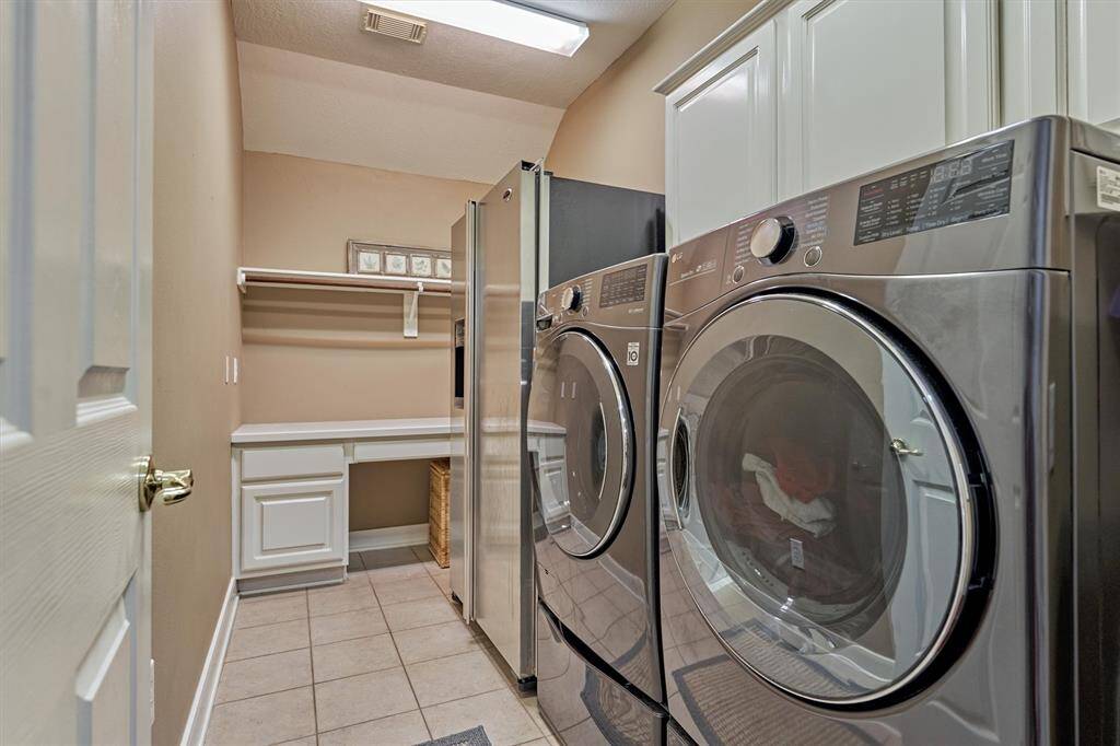 The laundry room offers a folding area and storage solutions with room for your extra refrigerator.