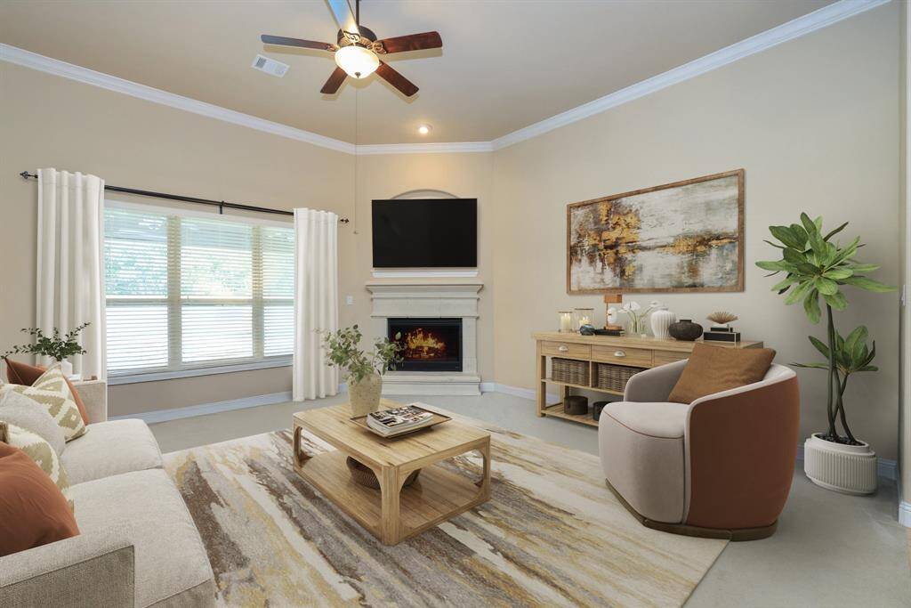 Family room with carpet and triple windows, crown molding and overhead fan.
