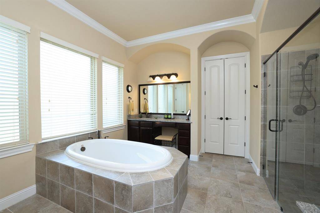 Soaker tub with tile surround. Vanity with makeup area and seating and large mirrors.
