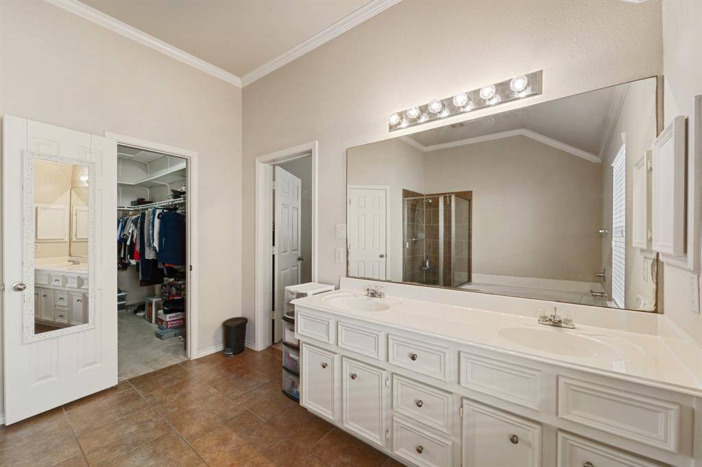 This luxurious primary bathroom features a double sink vanity with ample counter space, elegant tile flooring, and a spacious walk-in shower, offering both style and functionality for your daily routine.