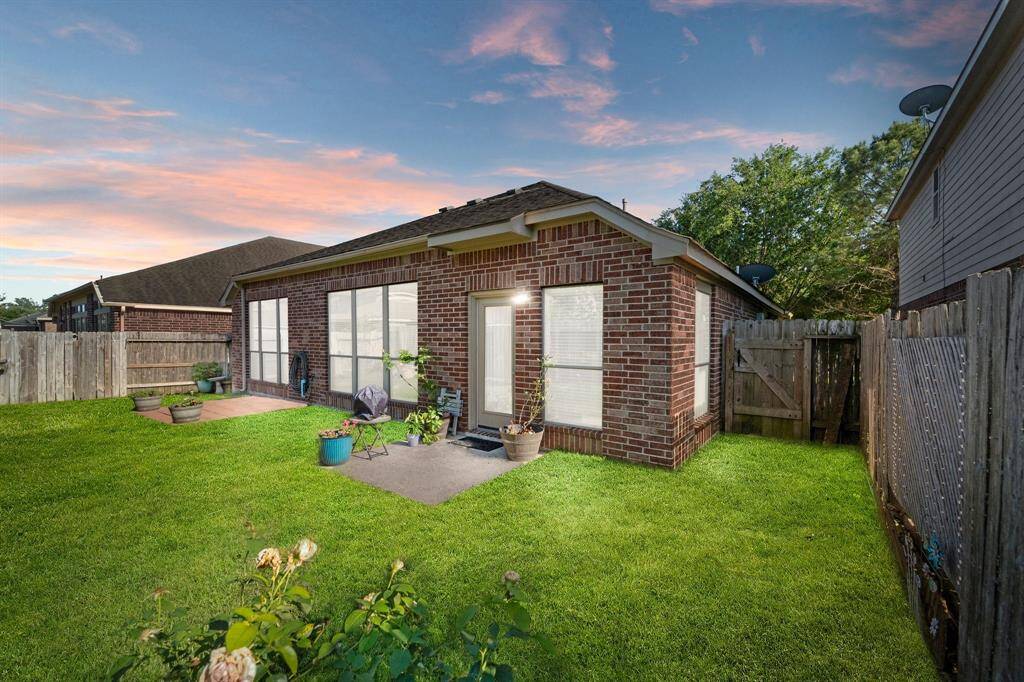The backyard is fully fenced, featuring a lush lawn and a charming patio, ideal for outdoor relaxation and gatherings.
