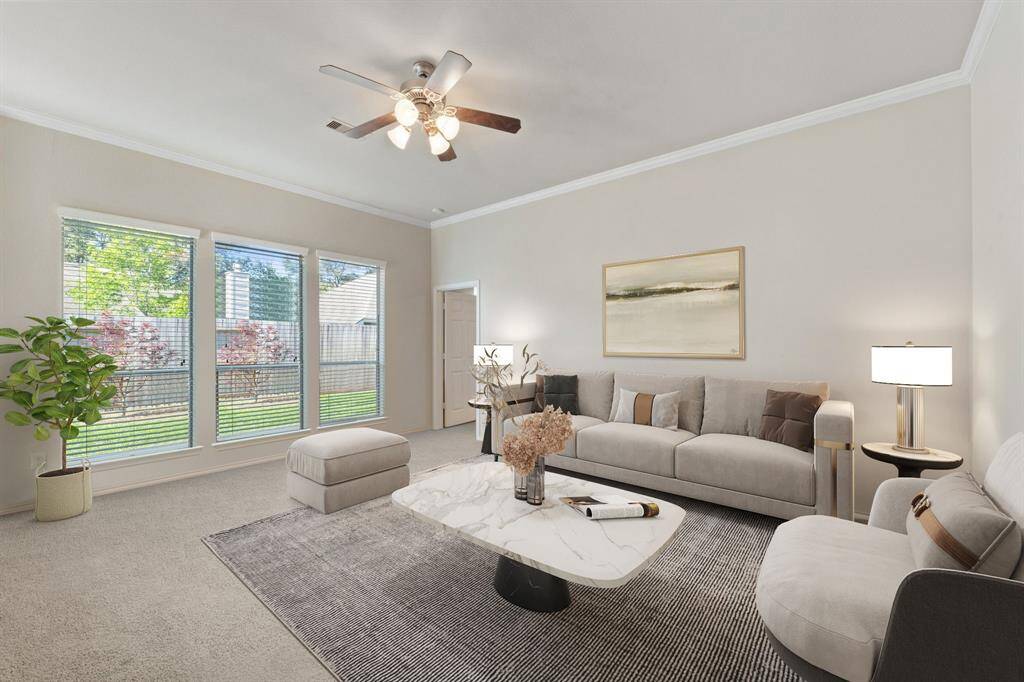 This inviting living room features multiple windows with privacy blinds that fill the space with natural light, plush carpeting for comfort, and elegant crown molding that adds a touch of sophistication. *Virtually Staged*