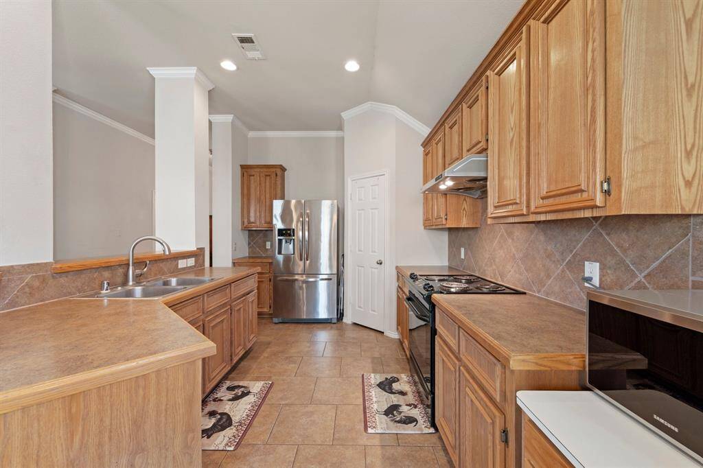 This charming kitchen features a convenient serving hatch perfect for entertaining, warm natural wood cabinets, sleek recessed lighting, and easy-to-maintain tile flooring—blending function and style for everyday living.