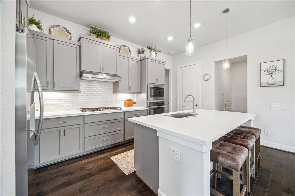 Tall gray cabinets with undermount lighting, Quartz countertops, stylish back splash. And look at those shiny stainless steel appliances. They shine inside and out.