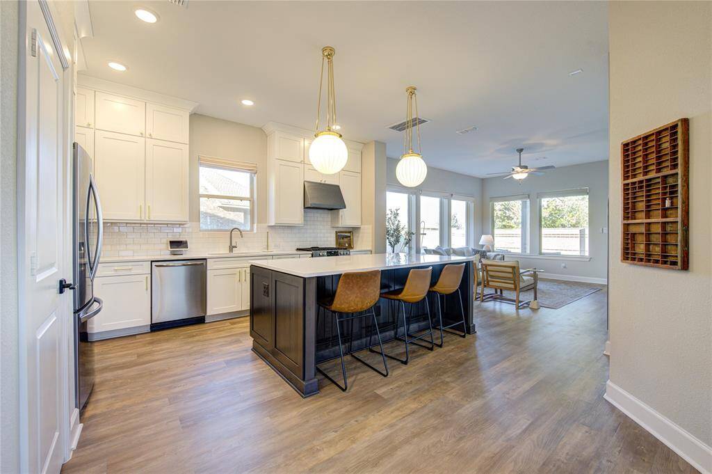 The custom white cabinetry extends to the ceiling, offering abundant storage while enhancing the kitchen’s sleek and sophisticated aesthetic.
