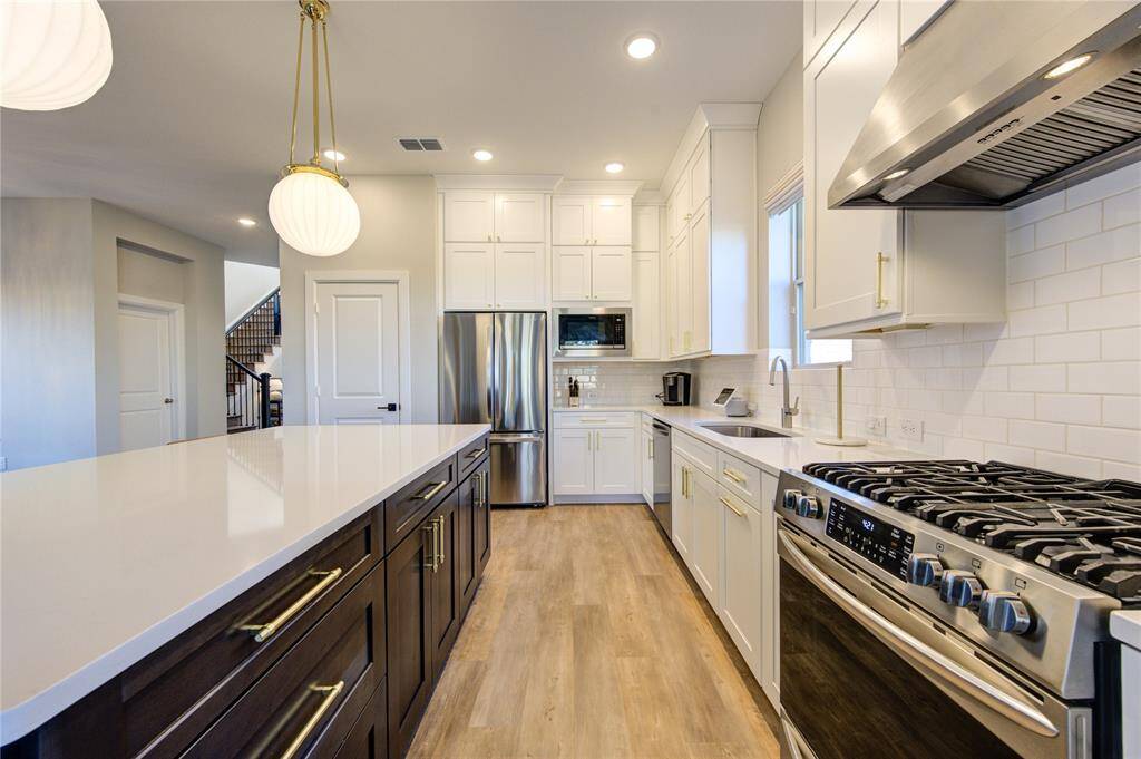 Outfitted with top-of-the-line stainless steel appliances, including a gas range, built-in microwave, and dishwasher for modern convenience.