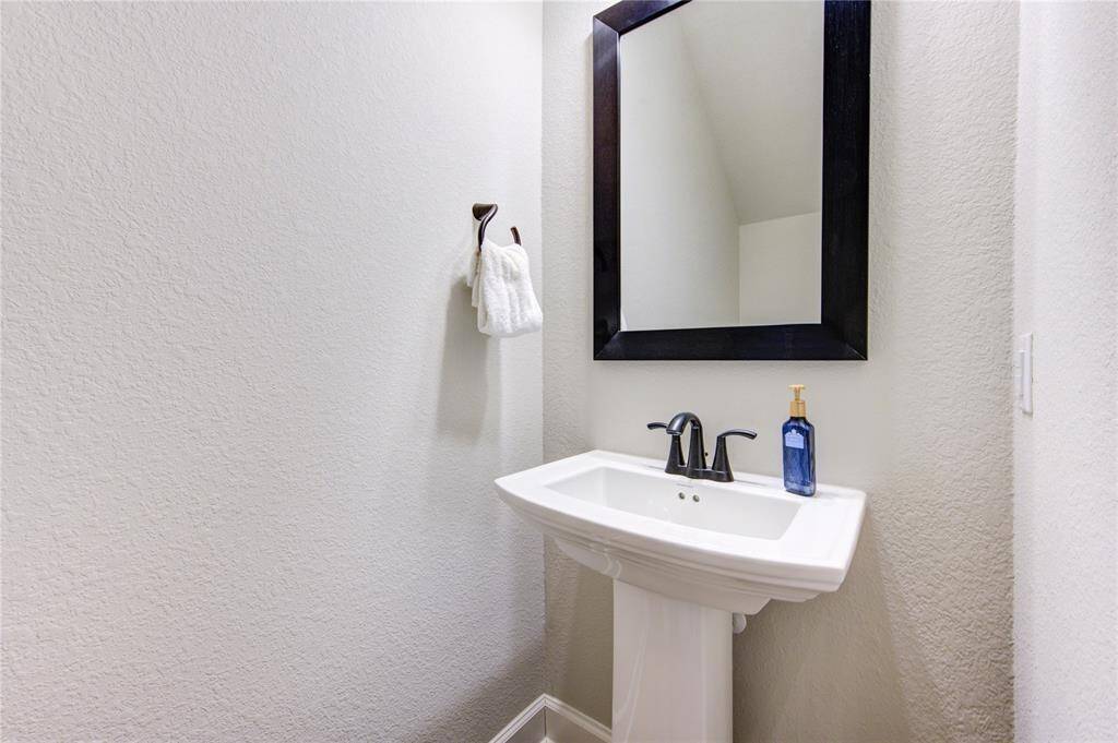 Positioned near the main living areas, this powder room provides easy access while maintaining privacy. A stylish mirror and contemporary hardware complete the look, making this a beautifully designed and practical addition to the home.