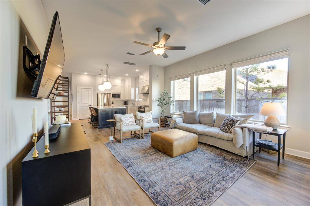 The open-concept living room is bathed in natural light from large windows with automatic blinds, offering scenic views of the private backyard with no rear neighbors.