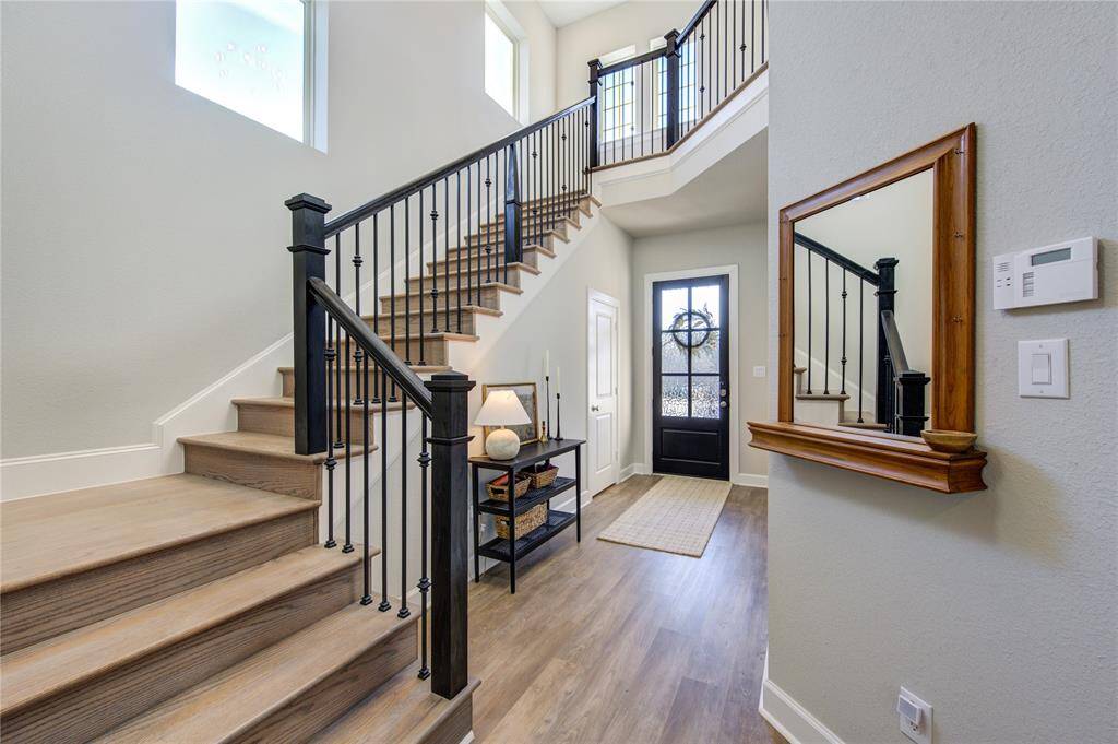 The inviting foyer showcases luxury vinyl flooring that flows seamlessly throughout the main living areas, offering both durability and elegance. The staircase also boasts LVP floors and wrought iron stair rails.