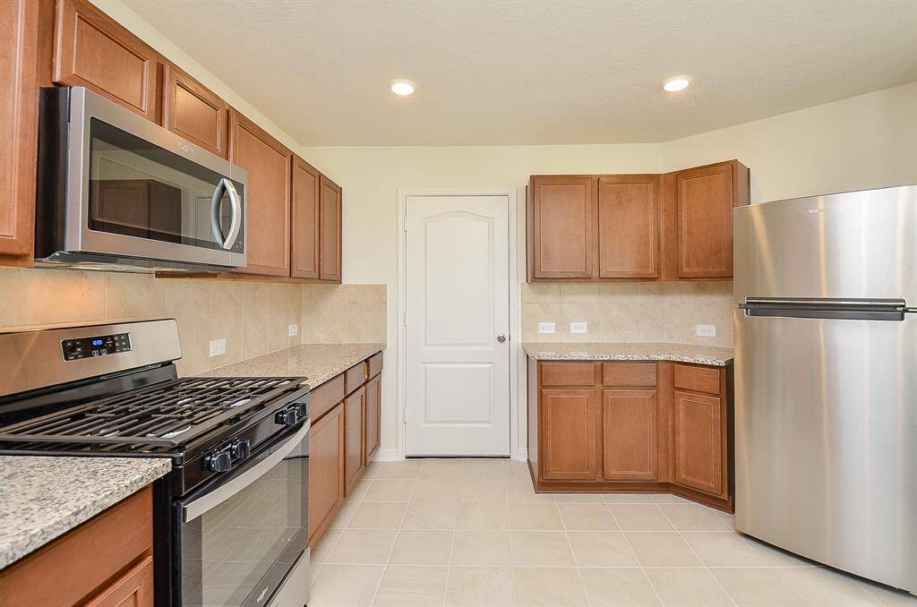 This modern kitchen features granite countertops, stainless steel appliances, and ample wooden cabinetry.