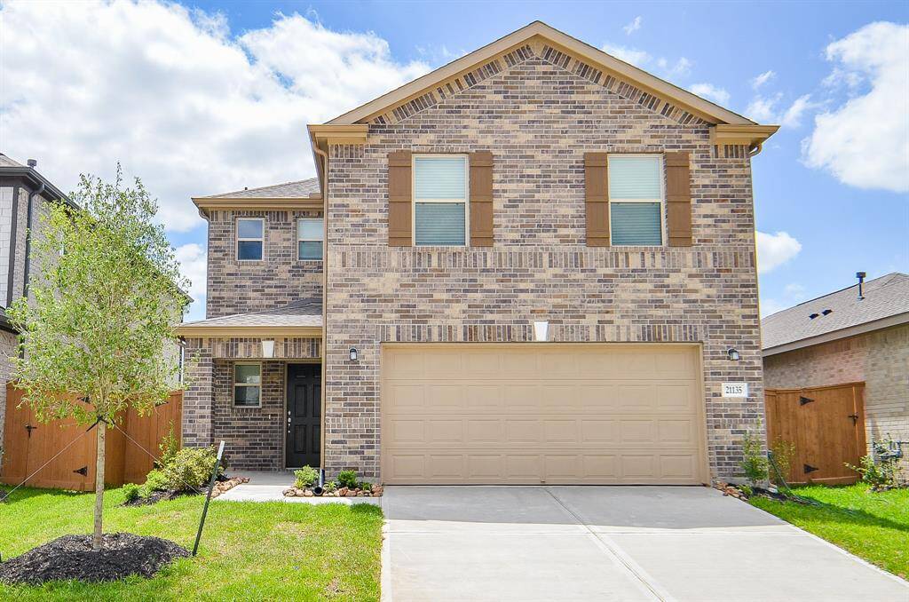 This is a modern two-story brick home featuring a two-car garage and a well-maintained front yard. It includes a welcoming porch and large windows, creating a bright and airy feel.
