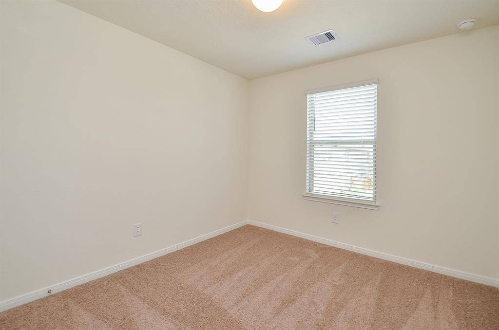 This second Bedroom features neutral walls, cozy carpeting, and a window with blinds that allows natural light to fill the space.