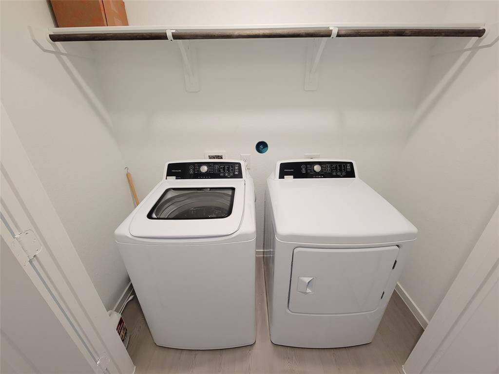 This is a dedicated laundry space featuring a modern washer and dryer set with ample overhead storage provided by a sturdy shelf.