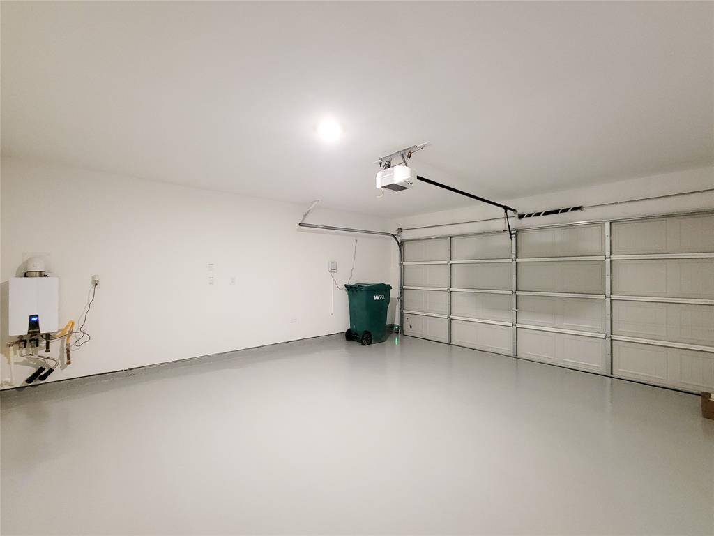 This is a clean, spacious two-car garage featuring a freshly painted floor, ample lighting, and a large door for vehicle access. The walls are white and unadorned, ready for customization or storage solutions.