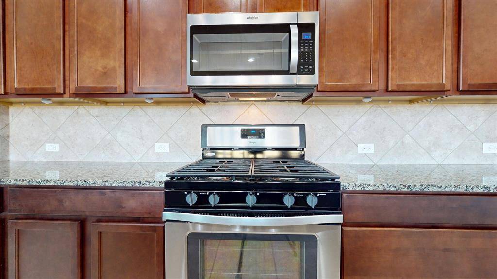 The kitchen features stainless steel appliances including the microwave and gas oven and cooktop.
