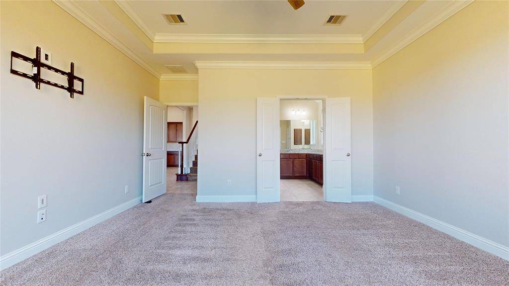The Primary bedroom features a ceiling fan and tray ceiling detailing. It includes wall mounts for a TV, double doors leading to an en-suite bathroom with dual sinks.