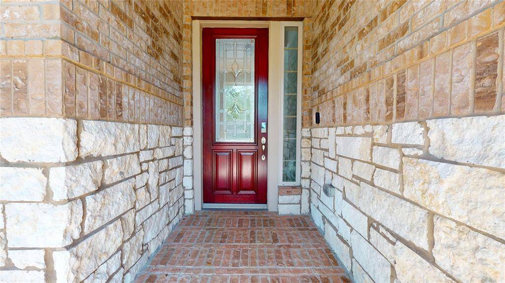 This is a welcoming front entrance featuring a door with decorative glass panels. The brick walkway adds charm and character to the entryway.