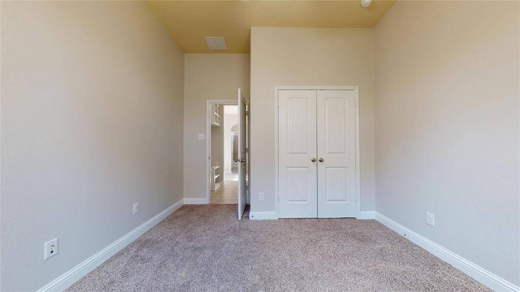 Guest Bedroom #1 features neutral walls and a double-door closet. A doorway leads to a hallway, providing easy access to the garage and utility room.