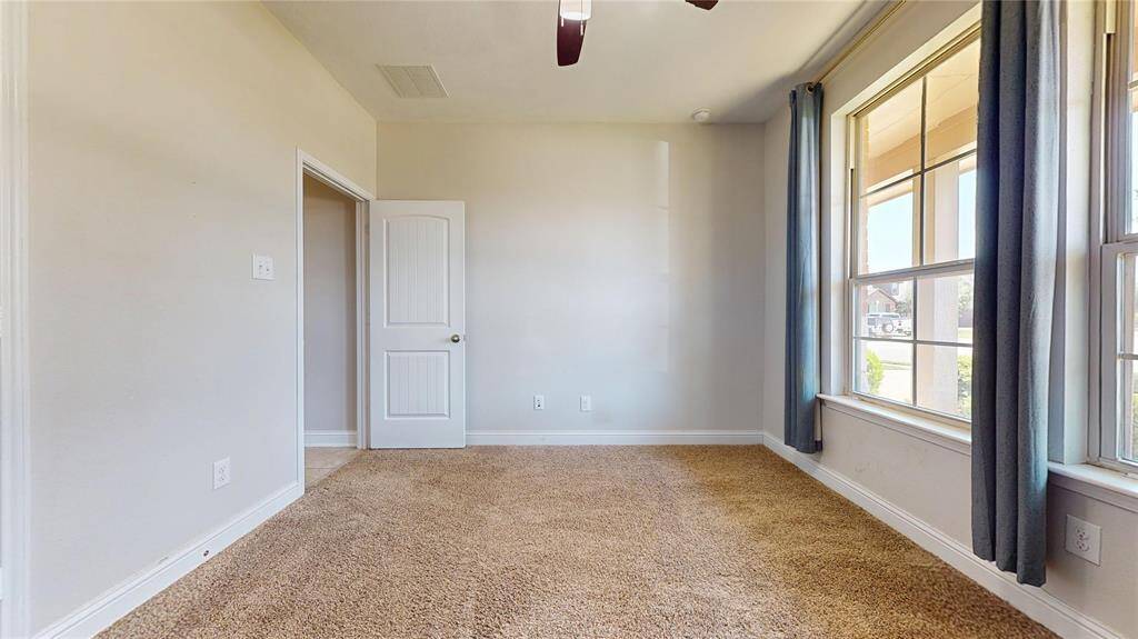 Guest bedroom #2 with large windows, neutral walls, and a ceiling fan. Ideal for an office or bedroom.