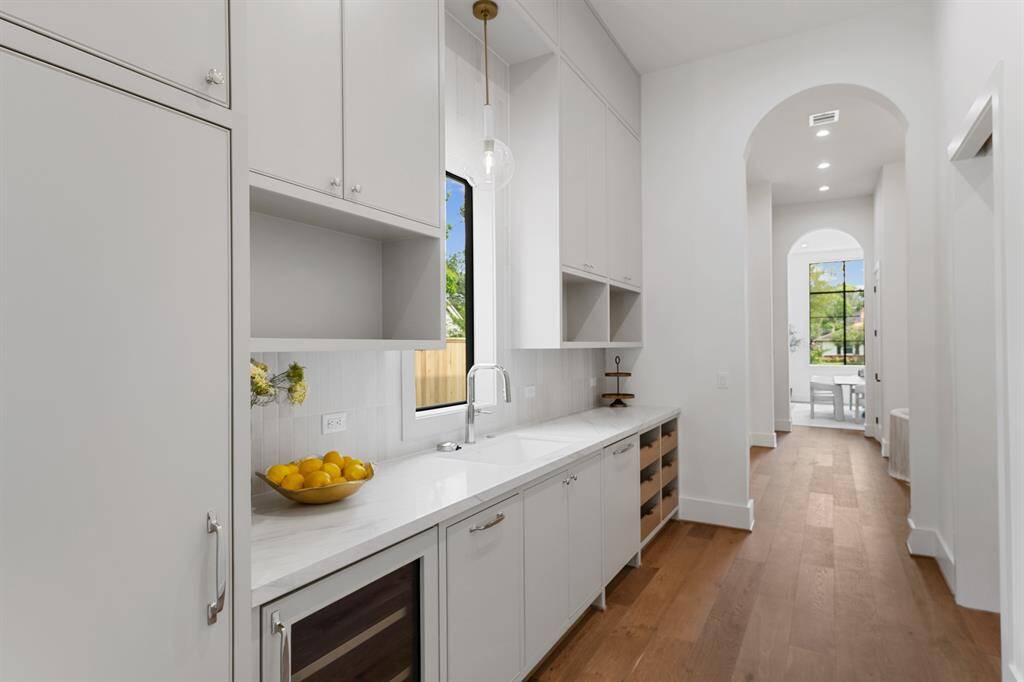 Tucked discreetly behind the main kitchen, the butler’s pantry offers a fully equipped staging space with a wine fridge, undermount sink with glass rinser, second paneled dishwasher, and generous custom cabinetry—perfect for effortless entertaining and everyday prep.