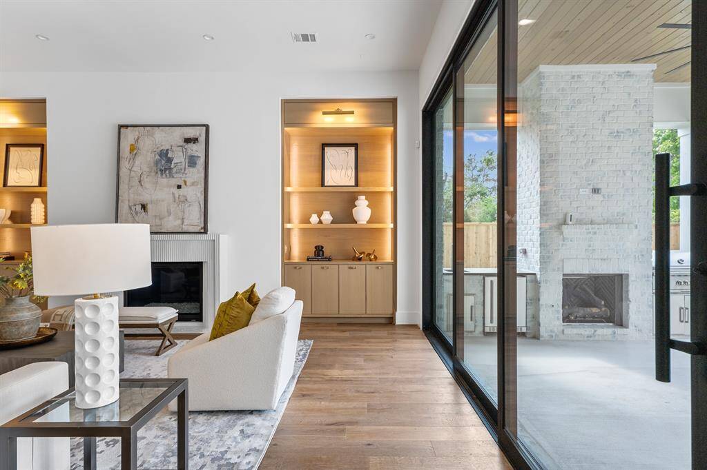 This living space is enhanced by oversized California sliding doors that flood the room with natural light and provide a seamless connection to the outdoors. The custom plastered fireplace serves as a striking focal point, adding warmth and a touch of modern elegance to the room.