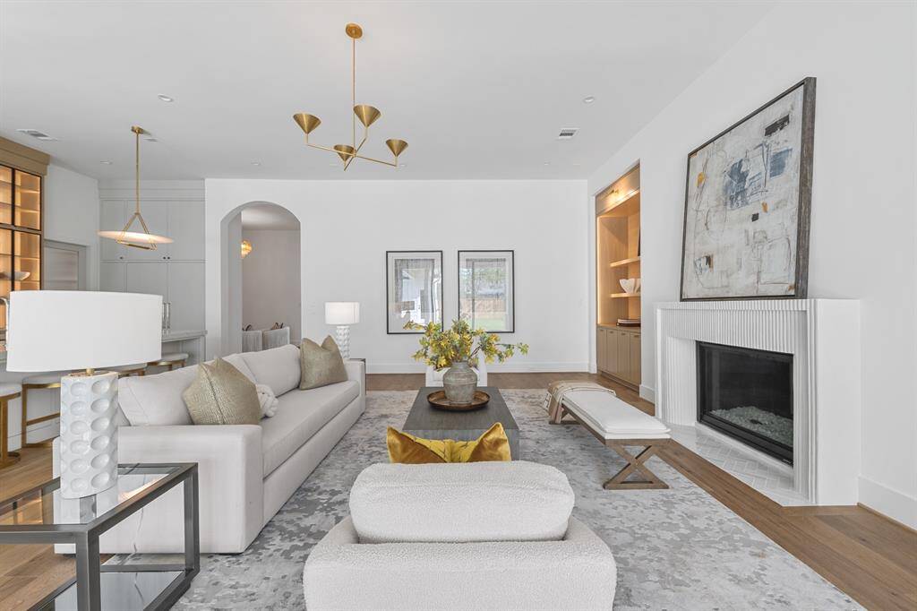 At the heart of the home, the main living space is a masterclass in refined comfort—where natural light pours in through expansive glass doors and highlights the bespoke plaster fireplace, white oak accents, and elevated finishes throughout.