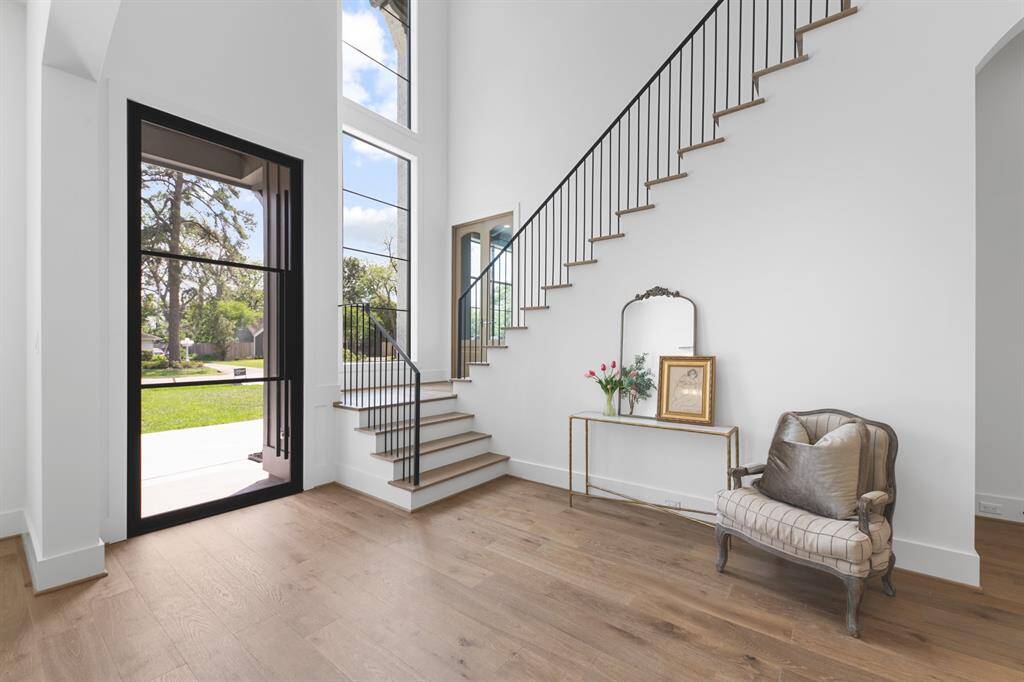This bright and inviting entryway is filled with natural light from expansive windows, highlighting the soaring ceilings and elegant design for a warm and welcoming first impression.
